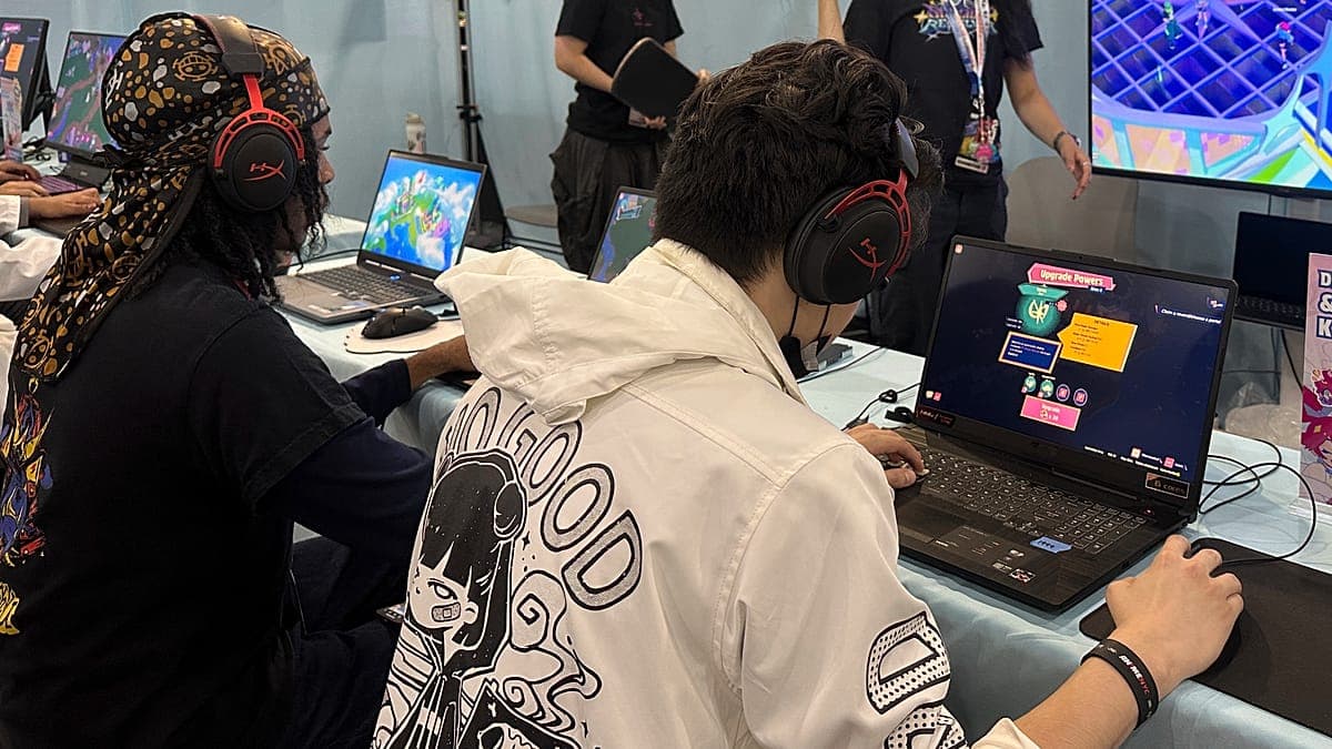 Para pemain muda mengenakan headphone gaming duduk di meja komputer bermain video game di sebuah acara atau kompetisi gaming.